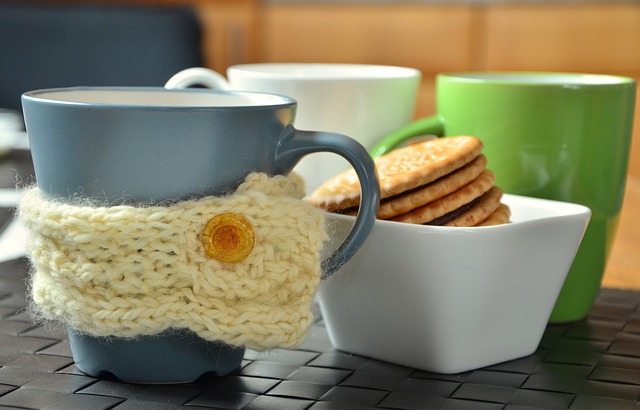 Coffee mugs with cup cosy and biscuits
